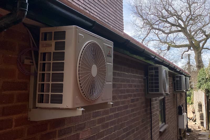Four external Mitsubishi air conditioner units along the side of a house.