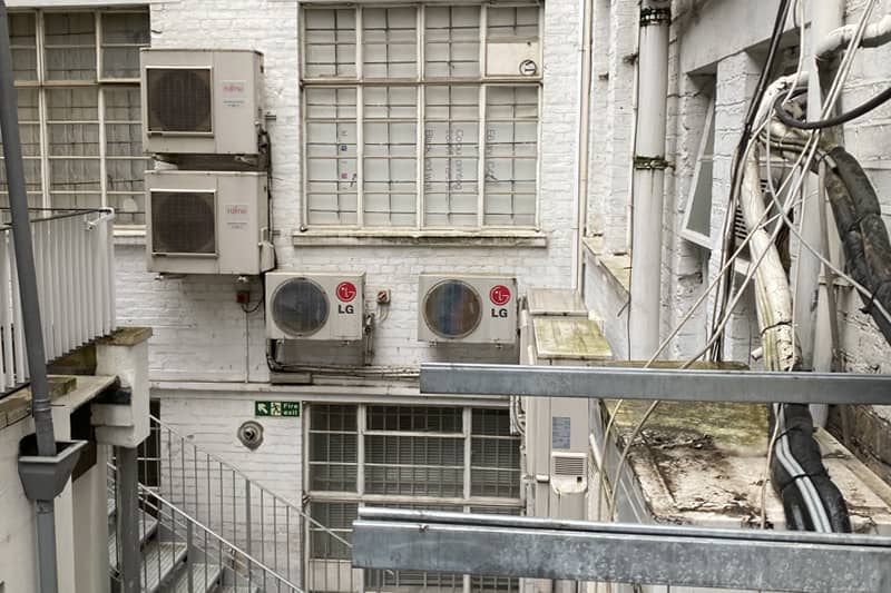 4 commercial air conditioning awaiting maintenance at the rear of a commercial property.