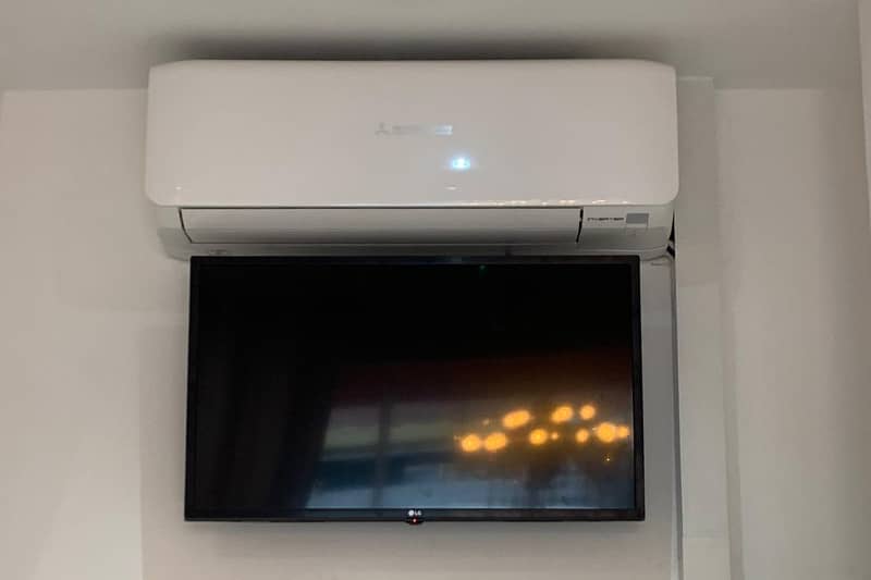 Wall mounted air conditioner install above a monitor.