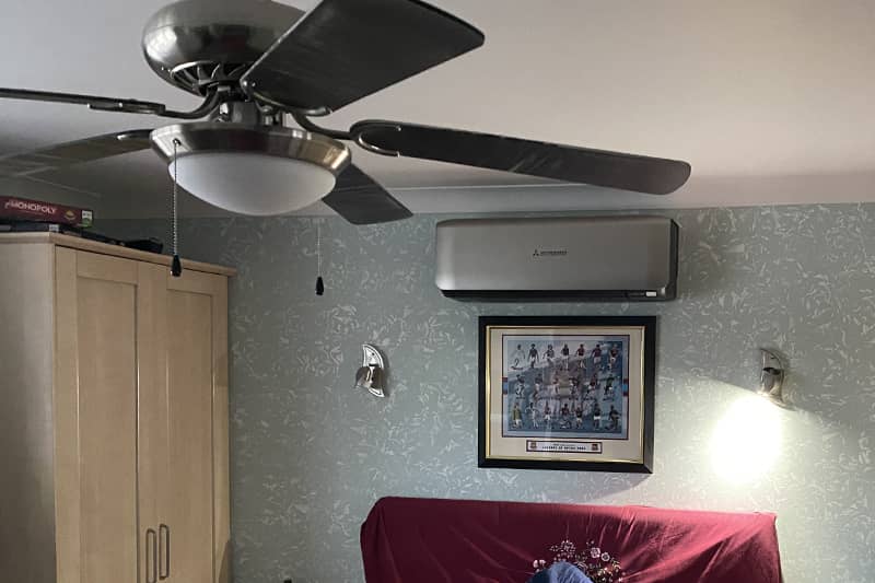 Wall mounted silver Mitsubishi air conditioner installed in a bedroom.