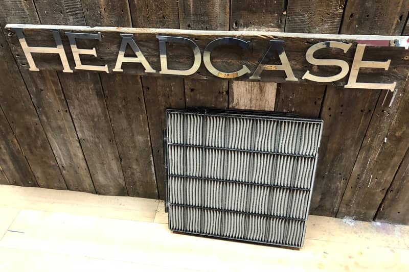 Air conditioning filter against a wood panelled wall at a London barbershop.