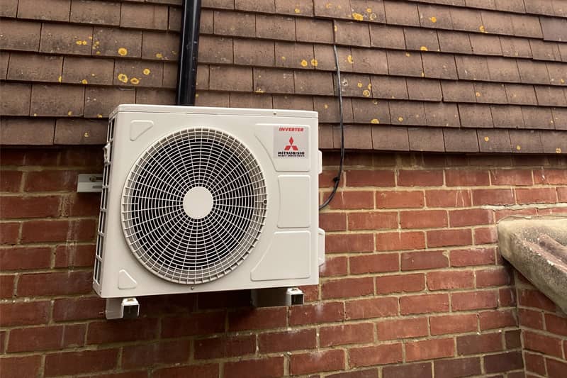 External Mitsubishi air conditioning inverter on a house wall.