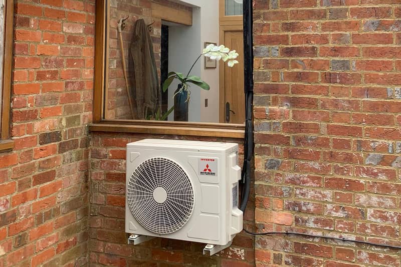 External Mitubishi air conditioner inverter installed at the rear of a home.