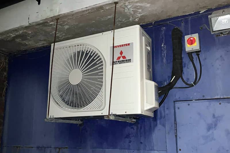 External Mitsubishi Heavy Industries air conditioning inverter on a blue wall