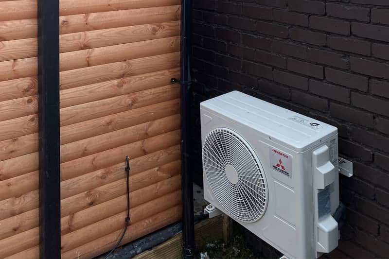 Misubishi air conditioning inverter installed on a garden wall.