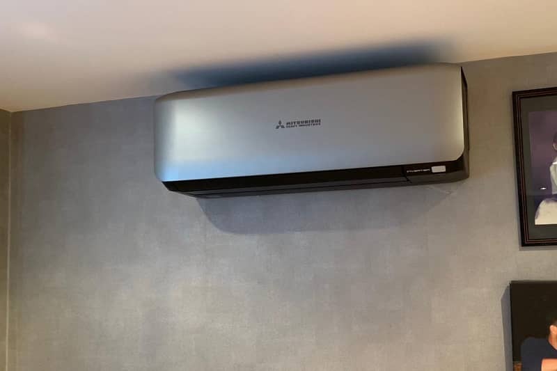 Silver wall mounted Mitsubishi air conditioner installed in a home.