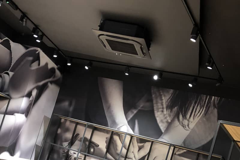 Black ceiling cassette air conditioner installed during a clothing store refit.