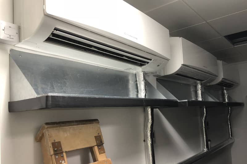 Three wall mounted air conditioner units installed in a server room.